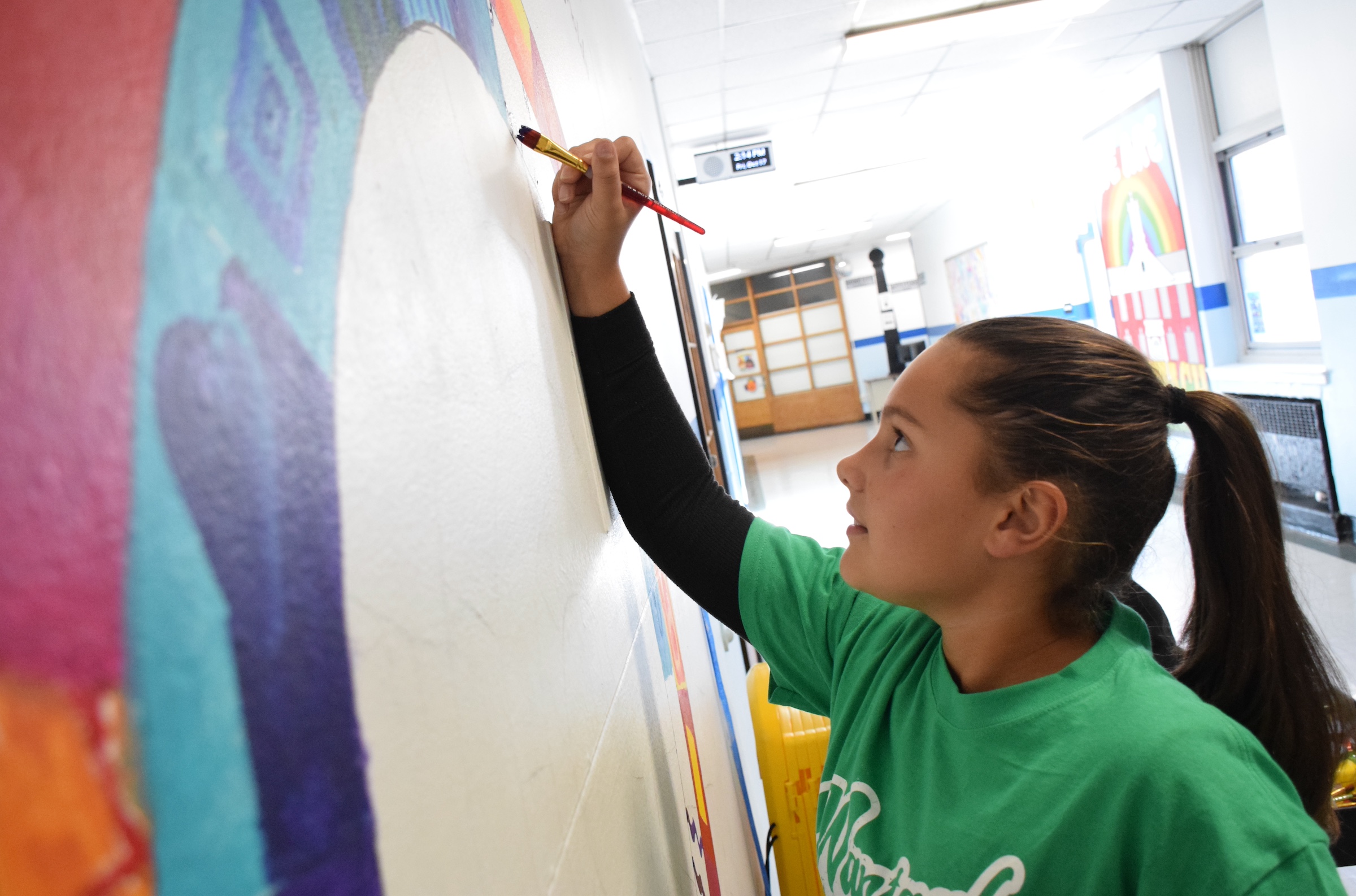 woman in green shirt painting on wall